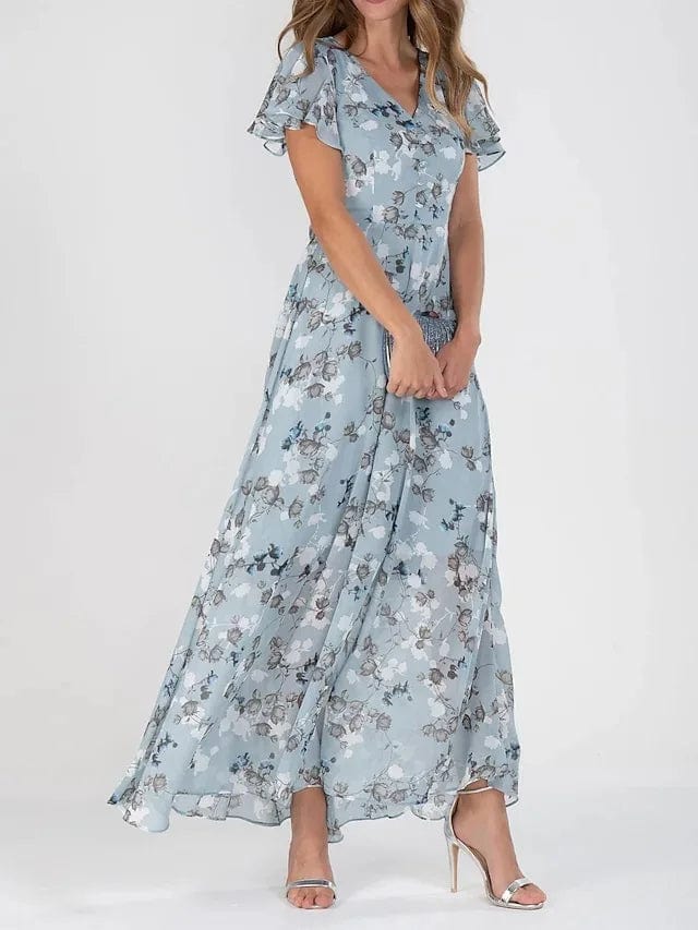 Side view, model in a colourful maxi summer dress with a V-neck and flutter sleeves, holding a small clutch