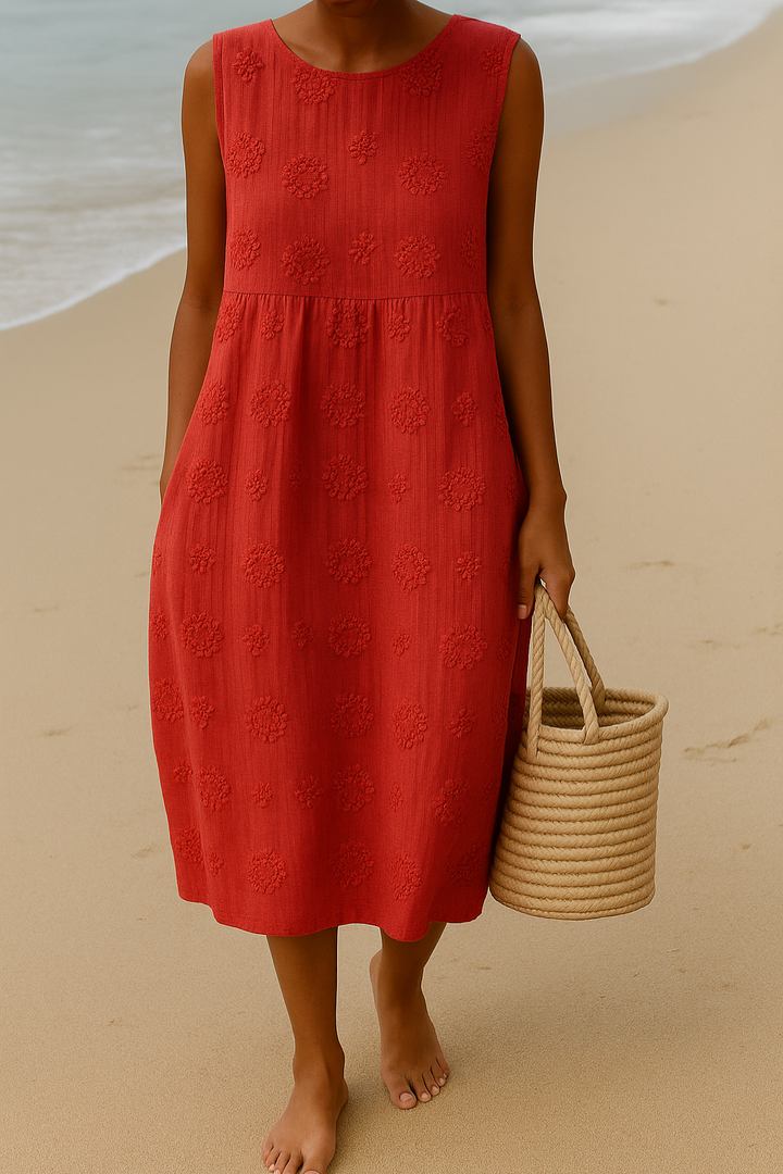 Front view of a model wearing the red sleeveless A-line boho dress with floral embroidery and a basket on the beach