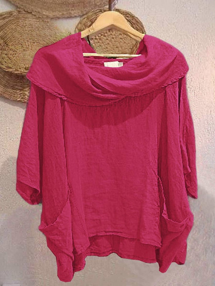 Front view of a fuchsia linen pocket top with a draped neck and 3/4 sleeves, held on a wooden hanger
