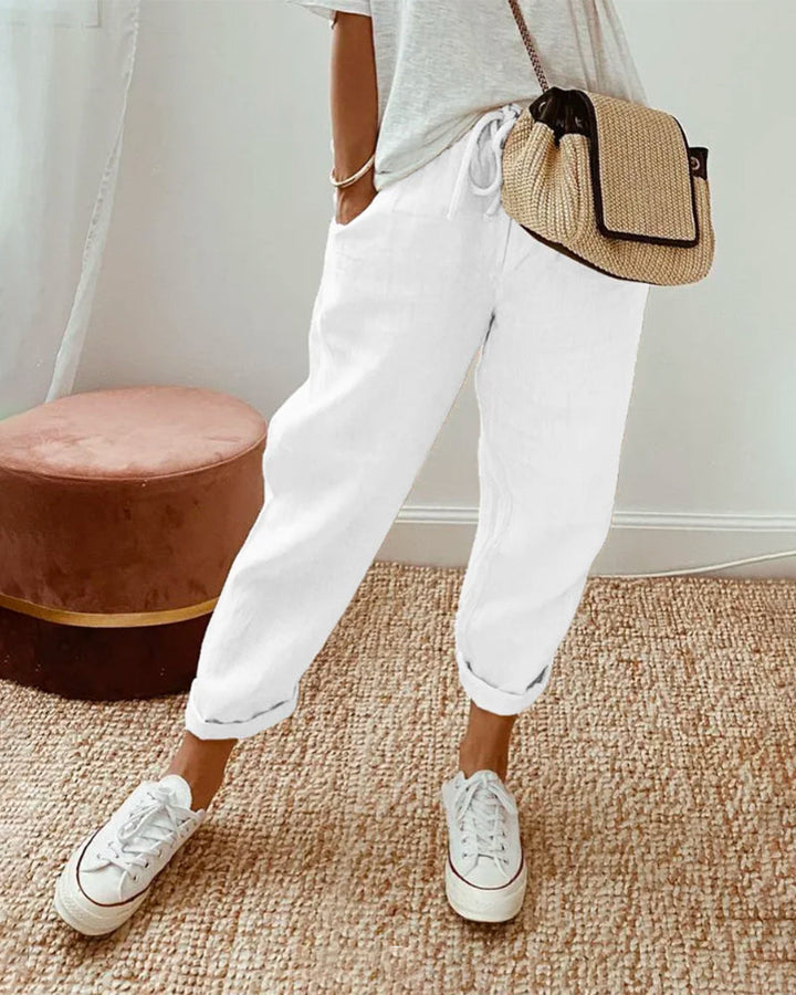 Carter Sweat-Wicking Linen Pants, close up worn by model, with white sneakers and a woven shoulder bag