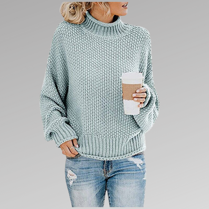 Front view of a model wearing the light blue Jovana Airy Touch Knit top with ripped jeans and holding a coffee cup