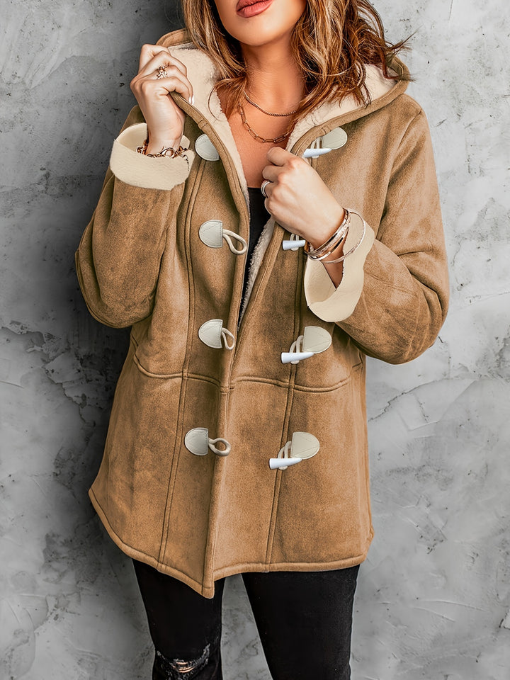 Front view of a model wearing a brown hooded toggle jacket with cream sherpa lining and cuffs