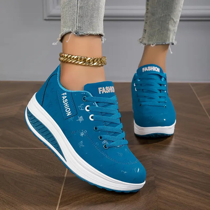 Three quarter view, worn by model, of blue Myrtle comfort sneakers with thick white soles and a gold ankle bracelet