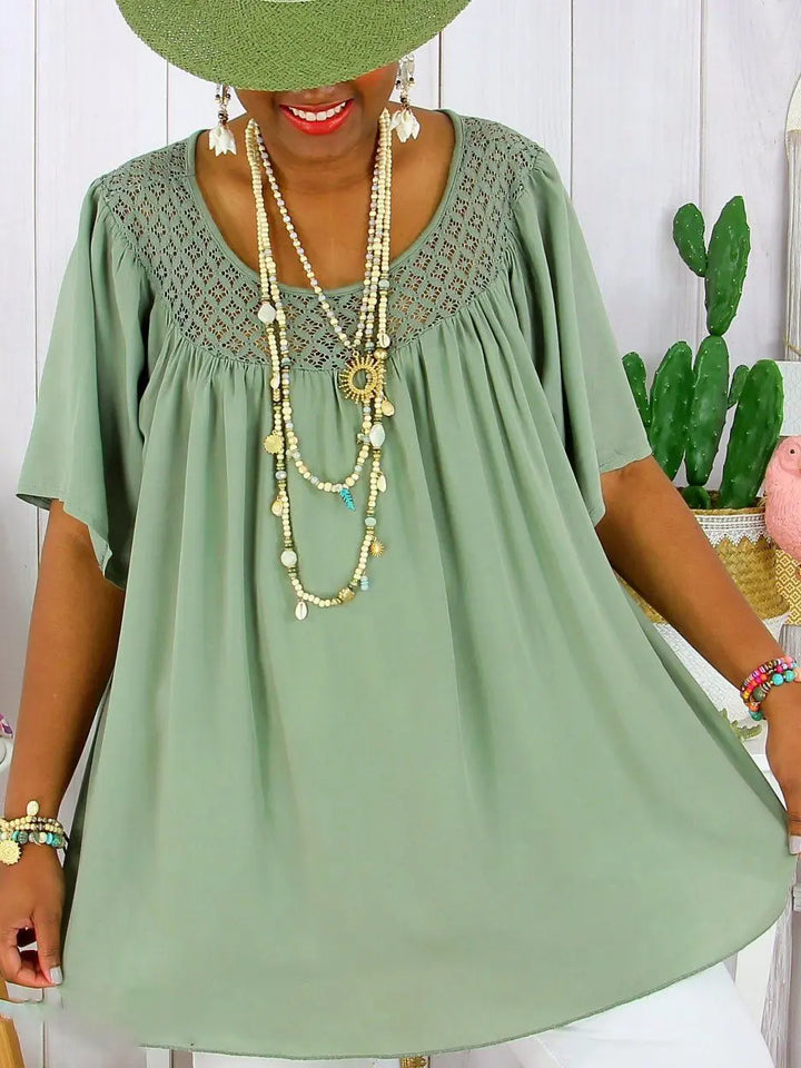 Front view, model wearing a sage green loose fit summer lace top with layered necklaces and a wide brim hat