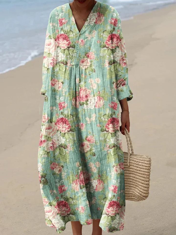Front view of a model wearing a purple boho floral print dress with a woven bag, standing on a beach