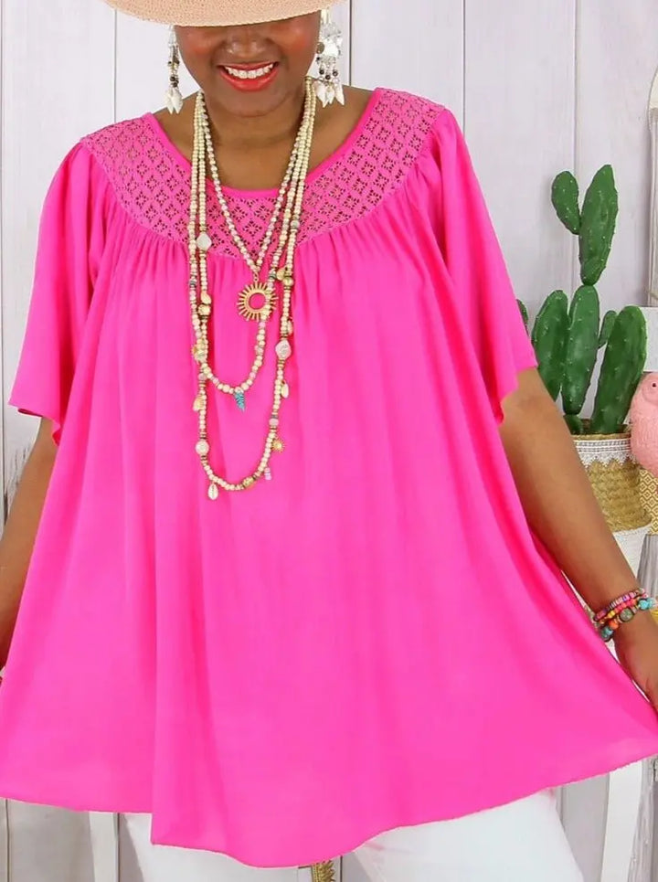Close up, model wearing a hot pink loose fit summer lace top with layered necklaces and a wide brim hat