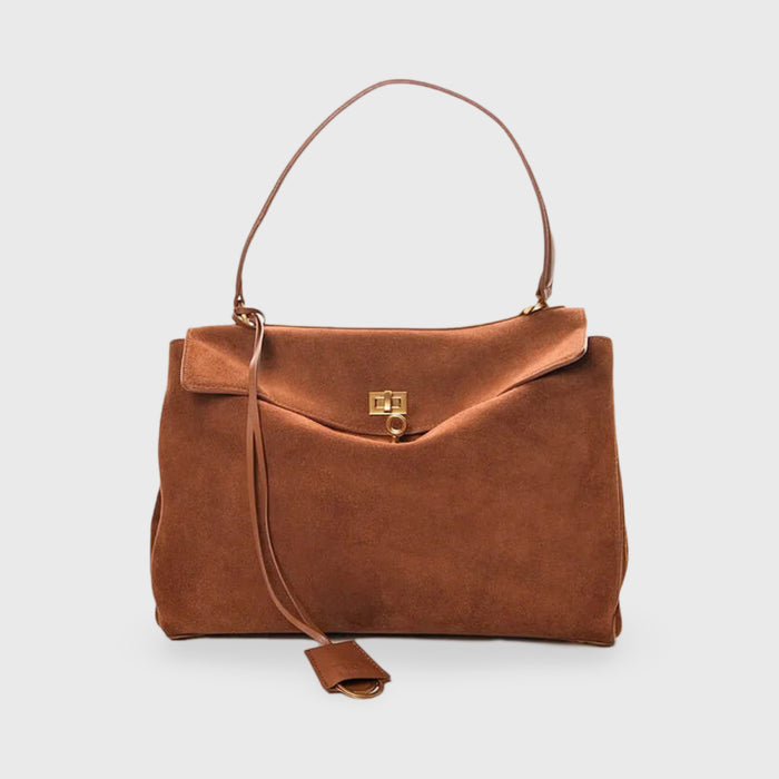 Front view of a brown suede shoulder bag with a top handle, gold clasp and long decorative strap