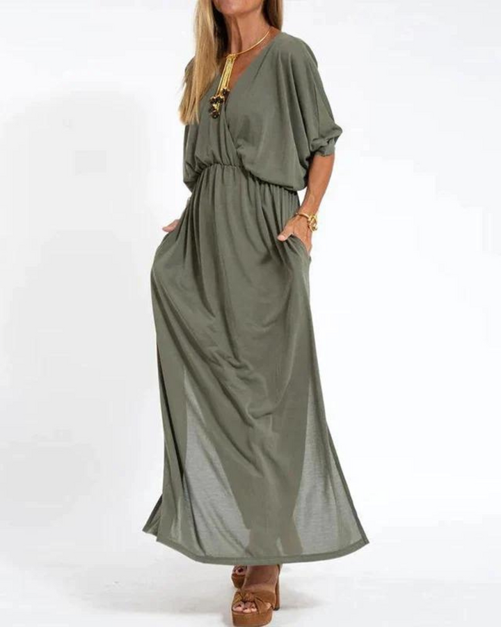 Front view of a woman wearing a khaki vintage high waist maxi dress with a V-neck and pockets, styled with heels