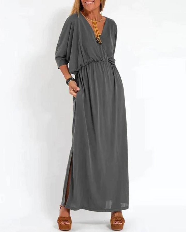Front view of a woman wearing a charcoal vintage high waist maxi dress with a V-neck, pockets and side slit