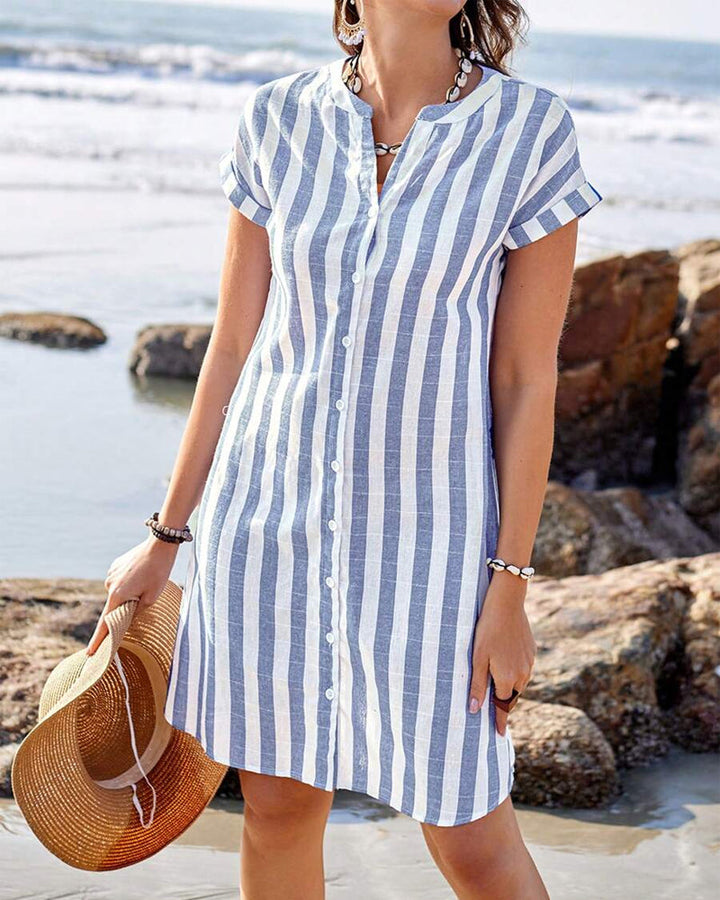 Front view of a model wearing a striped cotton linen short sleeve shirt dress on a beach