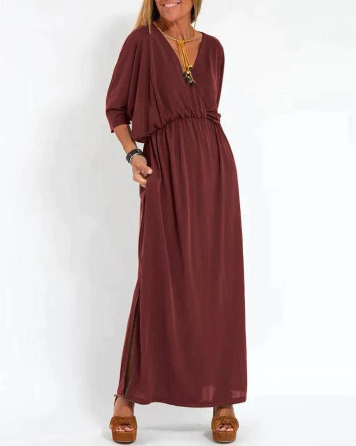 Front view of a woman wearing a maroon vintage high waist maxi dress with a V-neck, pockets and side slit