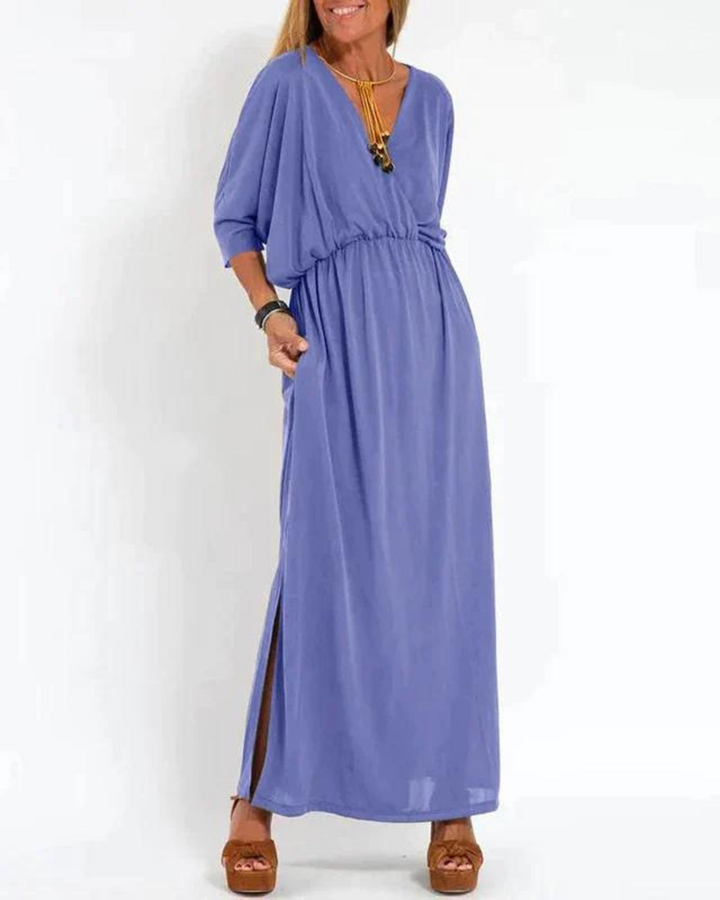Front view of a woman wearing a blue vintage high waist maxi dress with a V-neck, pockets and side slit