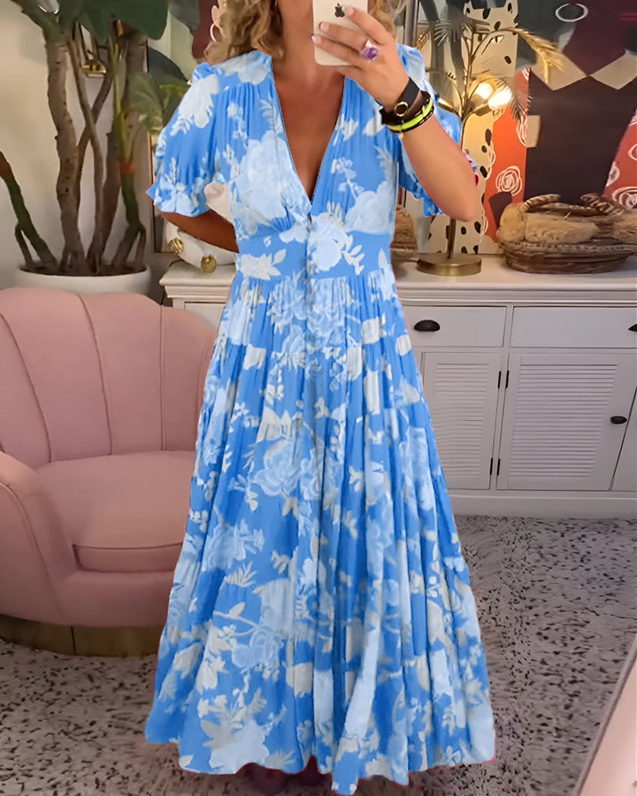 Front view of a model wearing a blue floral summer dress with a deep V neckline and short puffed sleeves