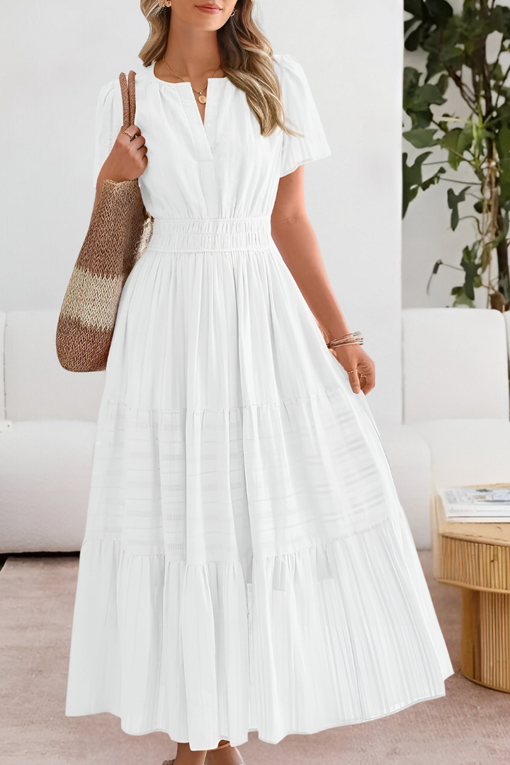 Front view of a woman wearing a white Boho Breeze summer dress with a smocked waist and tiered skirt, holding a bag