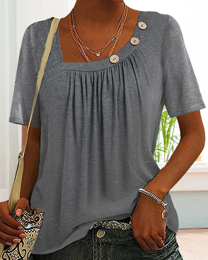Grey short sleeve blouse with a square neckline and decorative buttons, close up