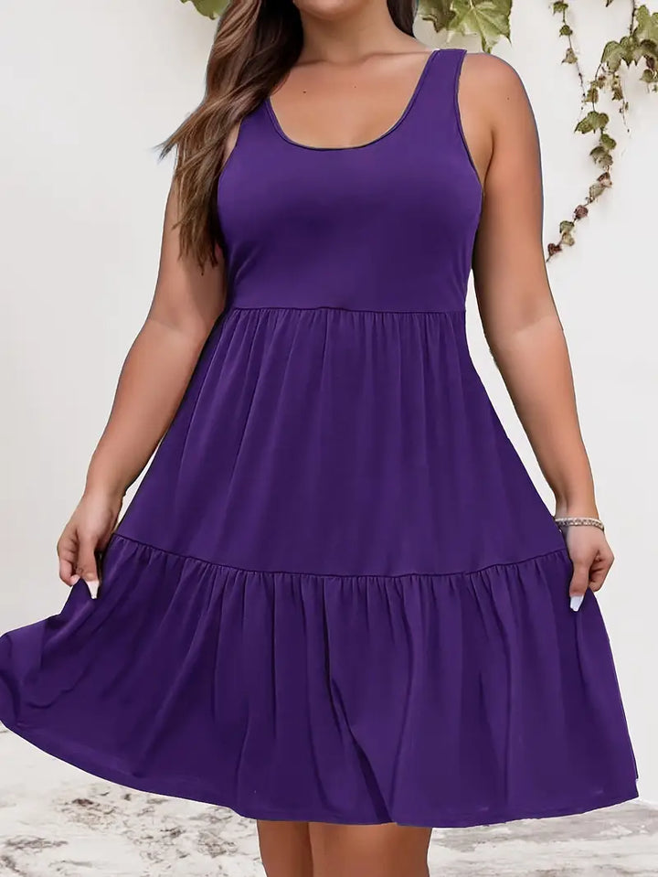 Front view of a plus-size model wearing a purple sleeveless tiered dress, hands lifting the skirt hem