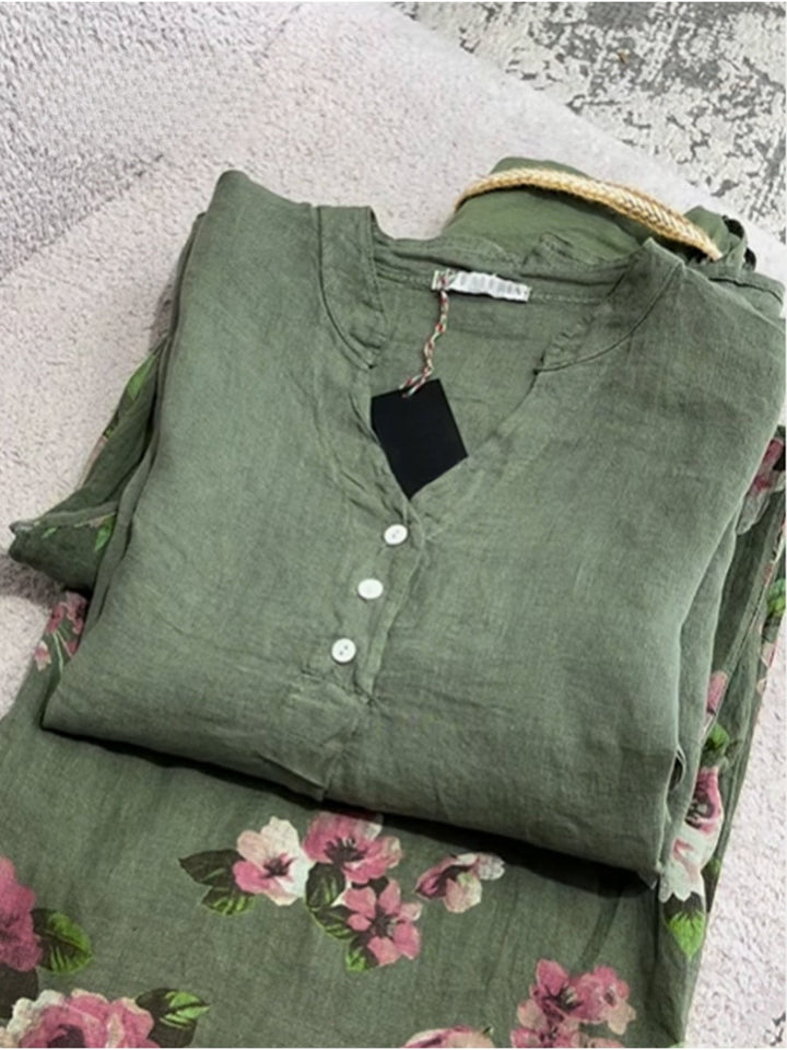 Front view of a folded green cotton linen shirt with a floral pattern and white buttons
