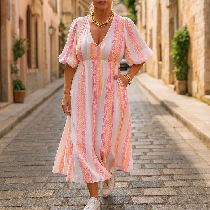 Front view of a model wearing a striped V-neck summer maxi dress with puffed sleeves and gold jewellery