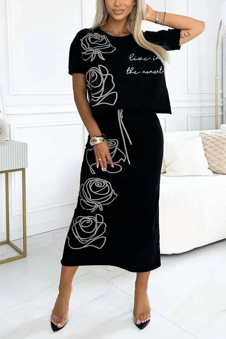 Front view of a model wearing a black floral print top and bustier skirt set with white rose outlines