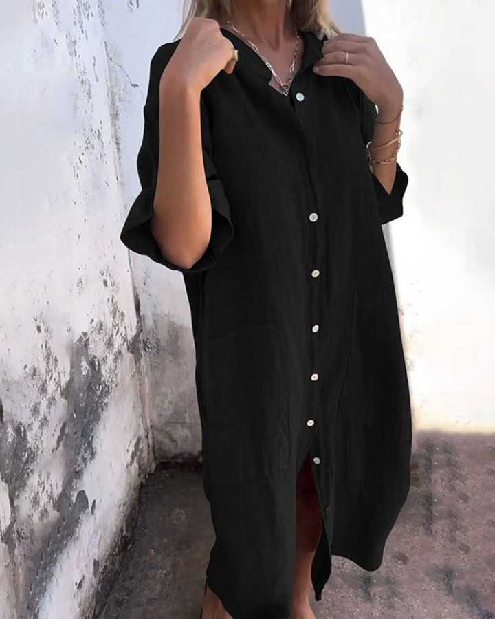 Front view of a model wearing a black cotton casual midi dress with white buttons and two front pockets