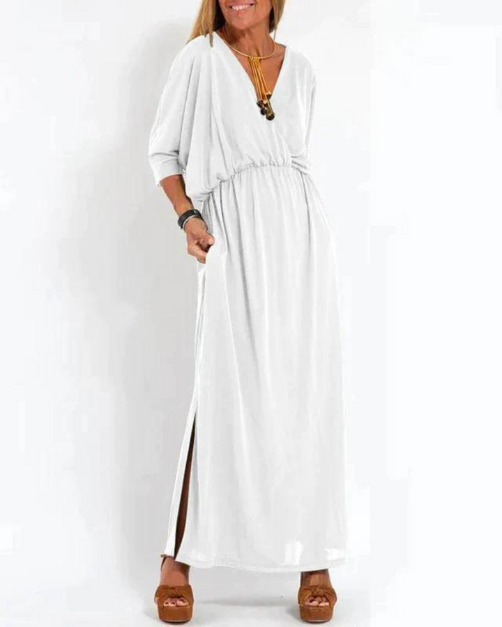 Front view of a woman wearing a white vintage high waist maxi dress with a V-neck, pockets and side slit