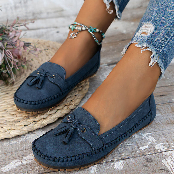 Worn by model, blue Zoe orthopaedic vintage loafers with tassels on a distressed white timber floor