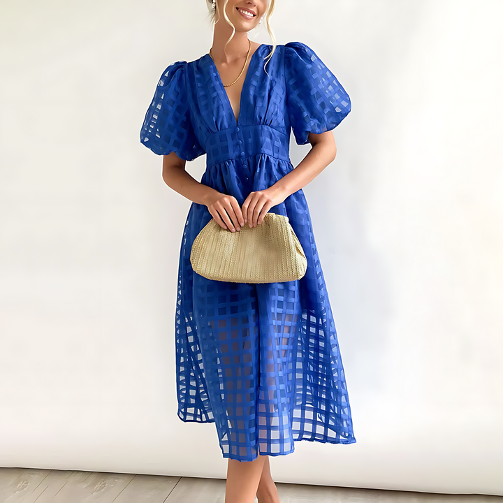 Front view of a model wearing an elegant blue summer midi dress with a textured woven clutch bag