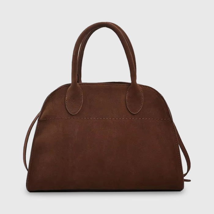 Front view of a dark brown suede mini bag with top handles and a subtle stitch detail on a light background