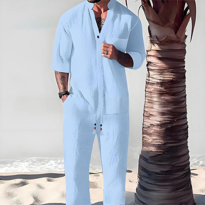Front view of a model wearing a light blue cotton-linen V-neck top and trouser set on a beach