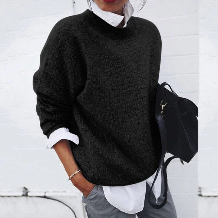 Front view of a model wearing a black oversized knit jumper over a white shirt with grey pants