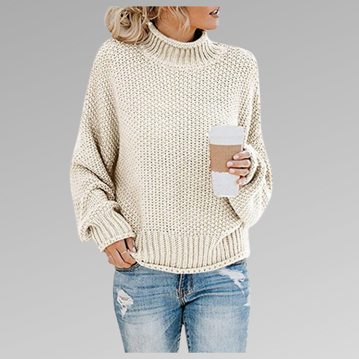 Front view of model wearing the cream Jovana Airy Touch Knit top with ripped jeans and holding a coffee cup