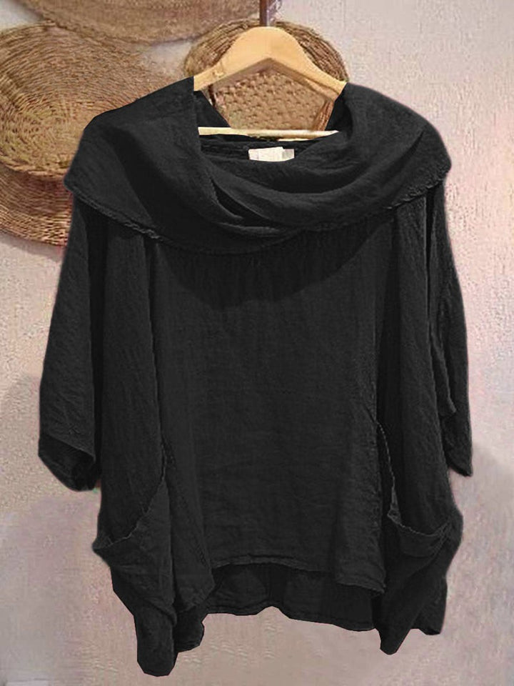 Front view of a black linen pocket top with a draped neck and 3/4 sleeves, held on a wooden hanger
