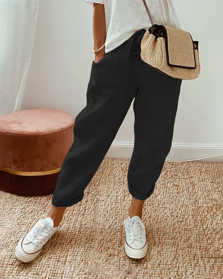 Carter Sweat-Wicking Linen Pants, three quarter view worn by model, with white sneakers and a woven bag