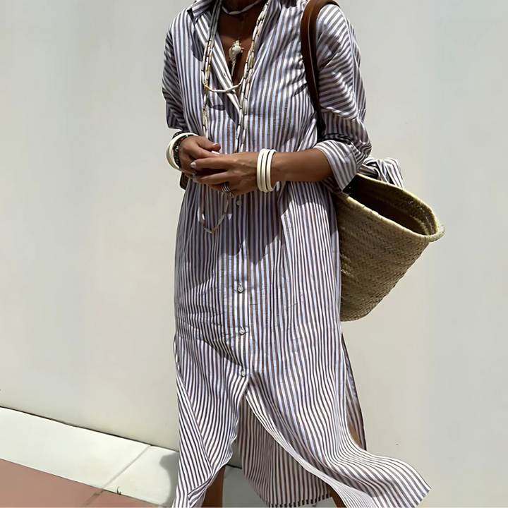 Detail of a striped shirt dress worn by a model, showing button-front and side split, with a straw bag