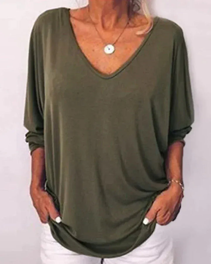 Front view of a model wearing a loose-fitting linen V-neck blouse in olive green with 3/4 sleeves