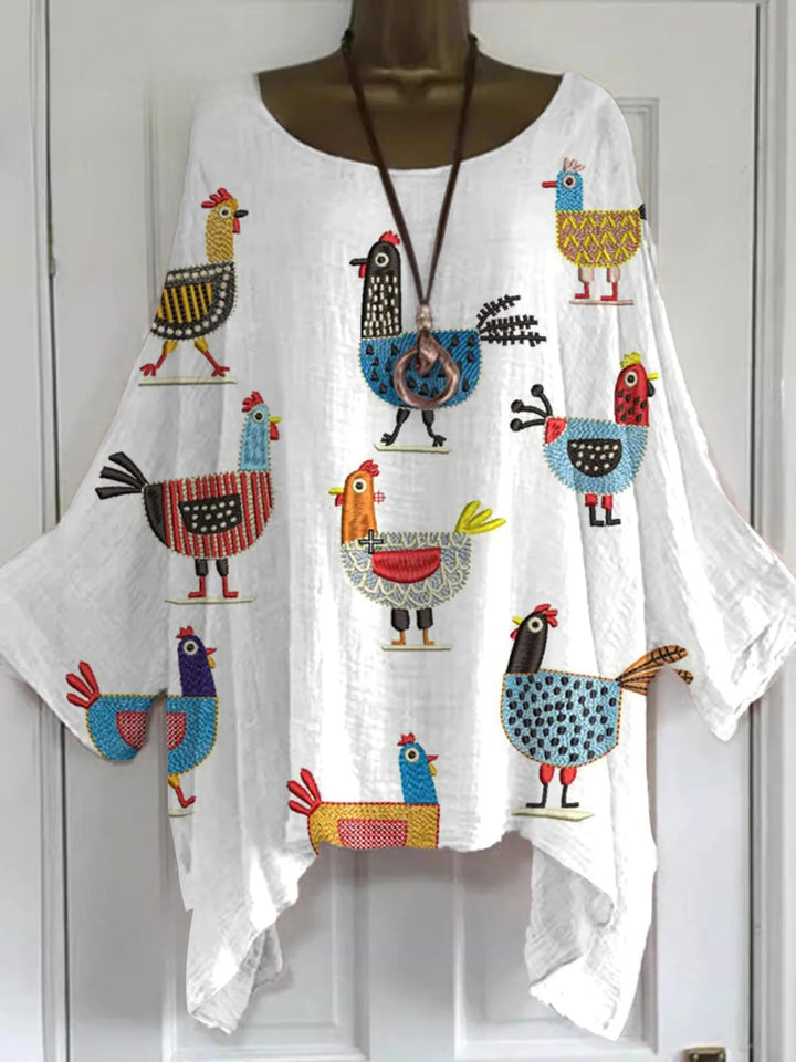 Front view of a white cotton linen shirt with nine colourful embroidered cartoon chickens and a long brown necklace