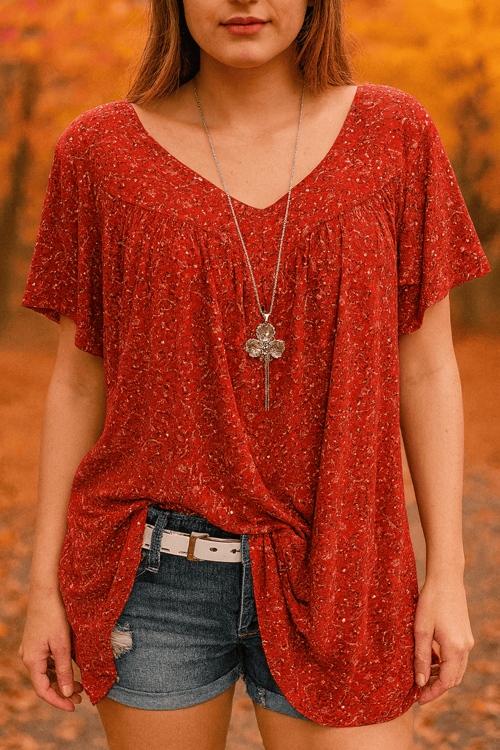 Burnt orange floral print blouse with a V neck, close up front view