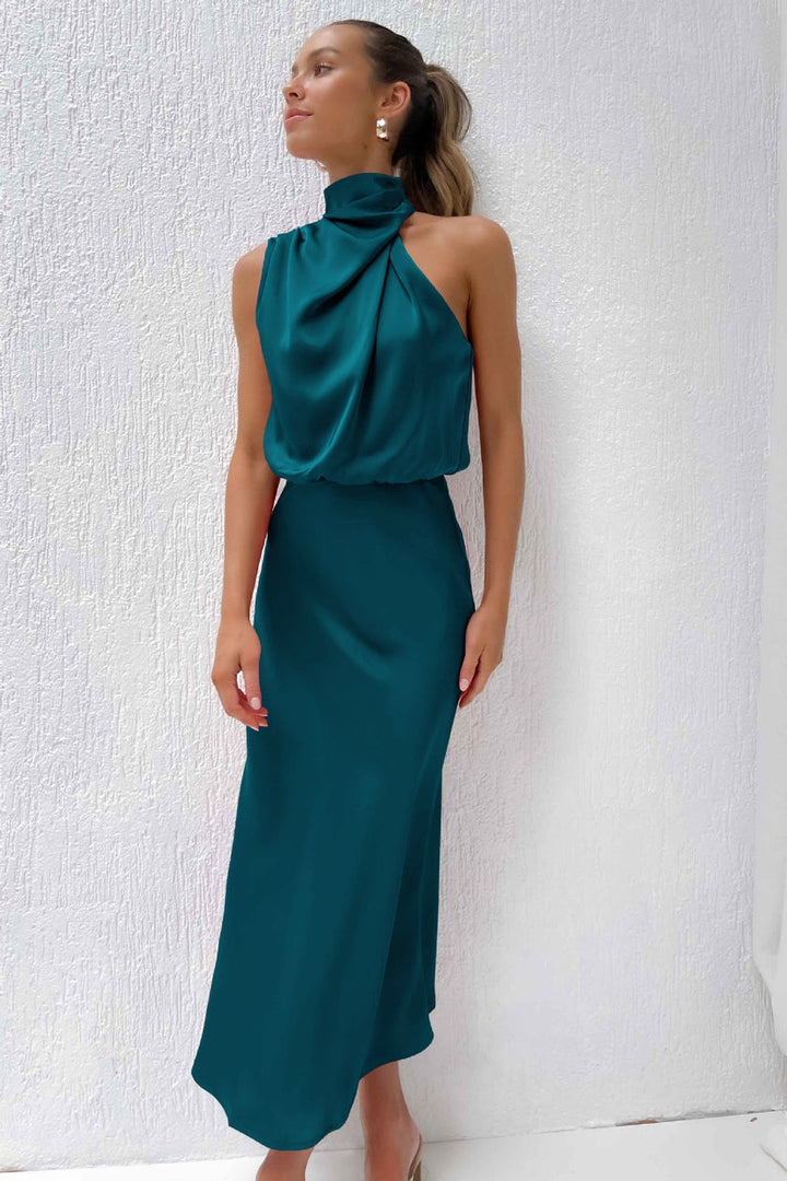 Front view, model wearing an emerald green long satin dress with a draped halter neckline and flowing skirt