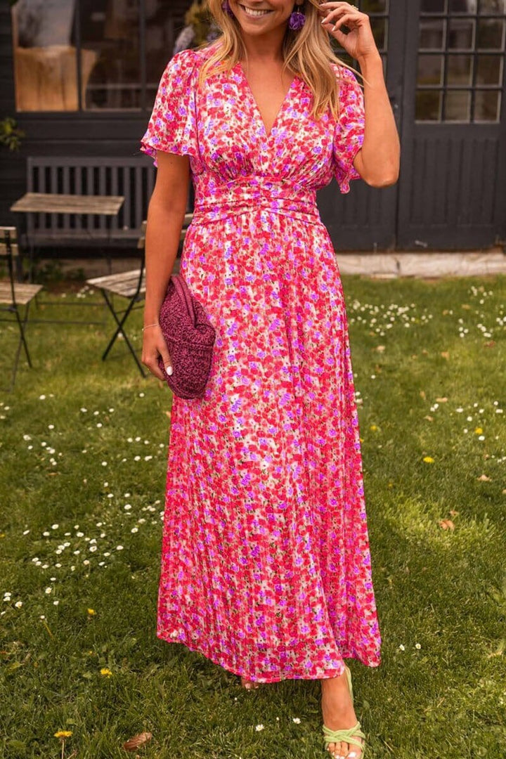 Front view of the Elegant V-Neck Maxi Dress, a vibrant pink floral dress on a model in a garden setting