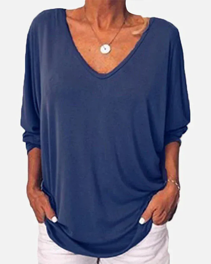 Front view of a model wearing a navy blue linen V-neck blouse with 3/4 sleeves and a round pendant