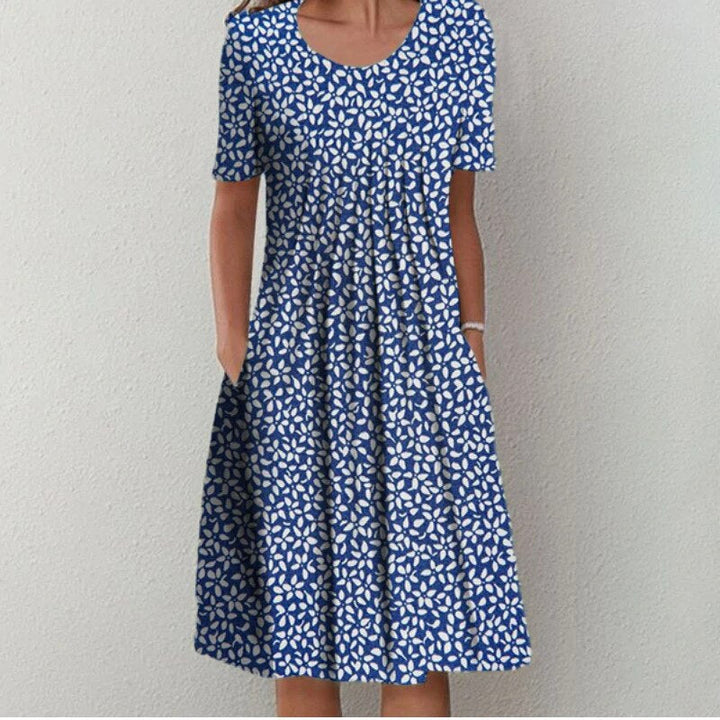 Front view of an elegant printed short-sleeved dress with a flared skirt and side pockets, worn by model, alternate angle