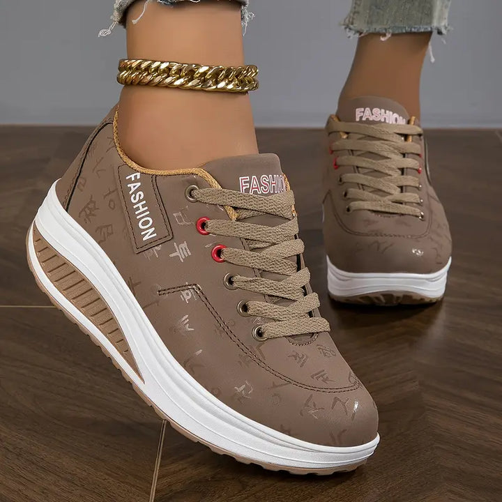 Three quarter view, worn by model, of brown Myrtle comfort sneakers with thick white soles and a gold ankle bracelet