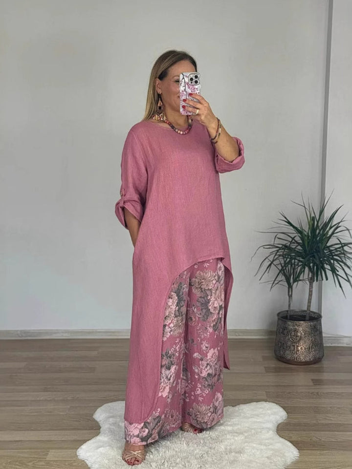 Front view of a model in a long-sleeve top and floral printed pants set, taking a mirror selfie indoors