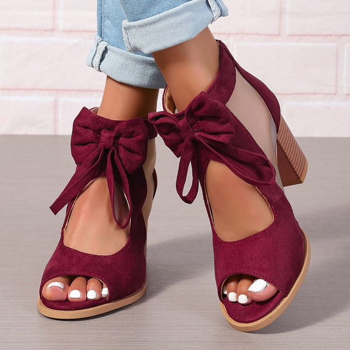 Front view of maroon chunky heel open-toe sandals with bows, worn by model