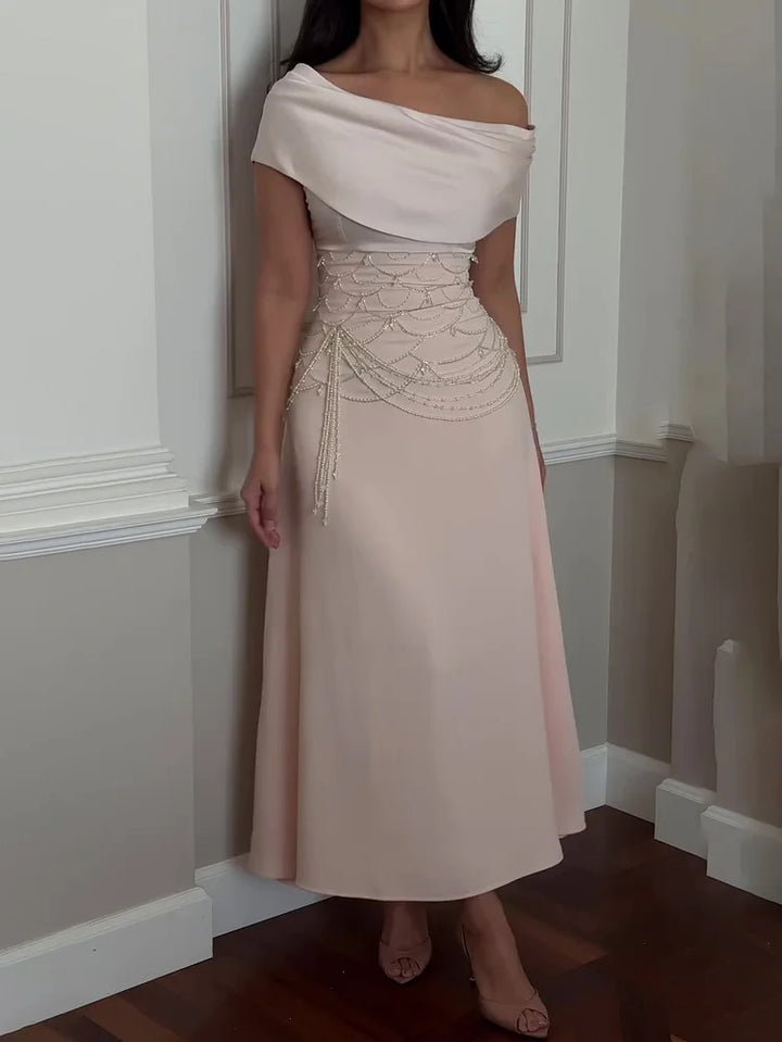 Front view of a model in a pearl beaded off-shoulder evening gown with draped bodice and waist details