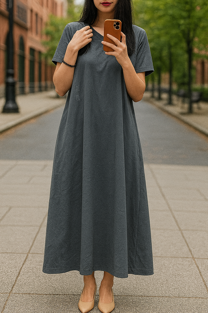 Front view, worn by model, of a flowing maxi dress in charcoal grey with a V neck and short sleeves