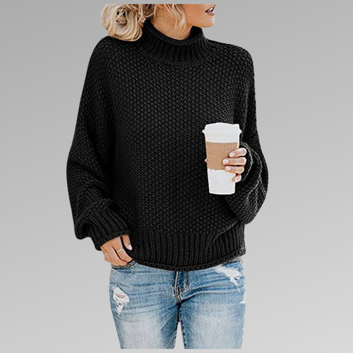 Front view of a model wearing the black Jovana Airy Touch Knit top with ripped jeans and holding a coffee cup