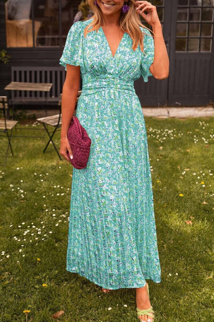 Front view of the Elegant V-Neck Maxi Dress, a blue floral dress on a model holding a magenta clutch outdoors