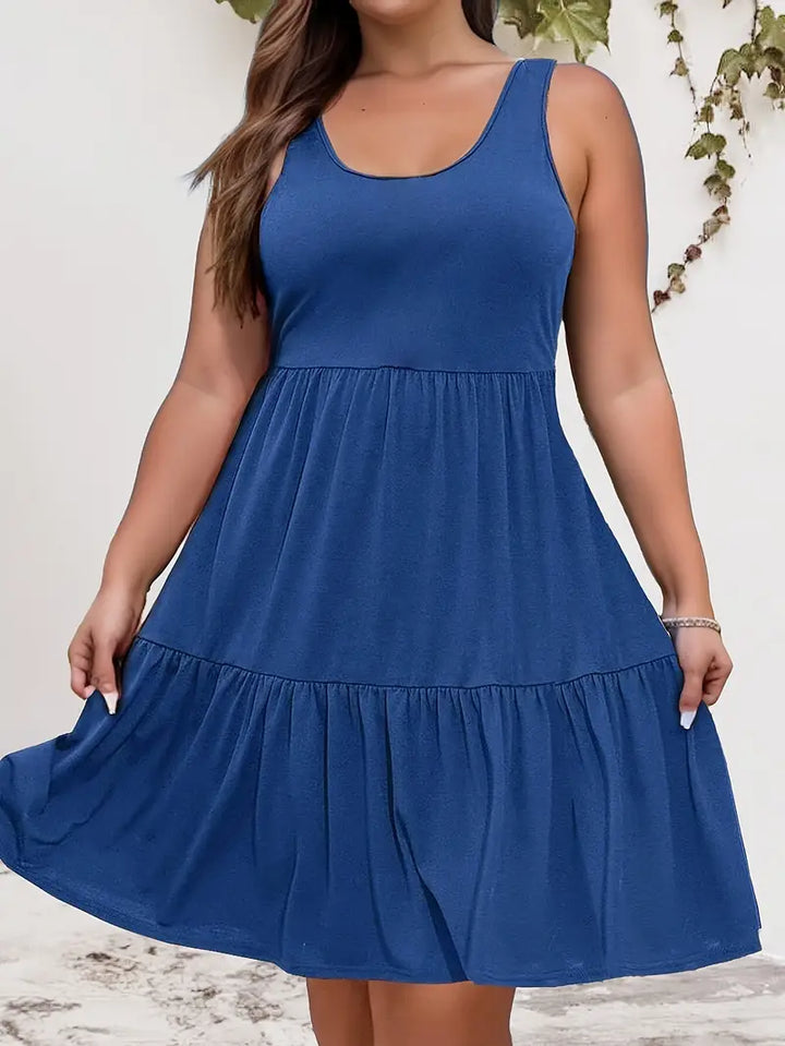 Front view of a plus-size model wearing a blue sleeveless tiered dress, showing the lightweight fabric