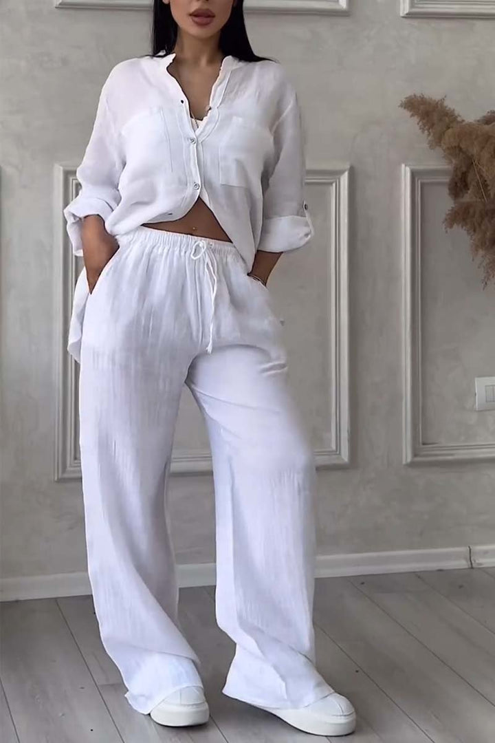 Front view of a model wearing a white long sleeve blouse and white wide leg pants set